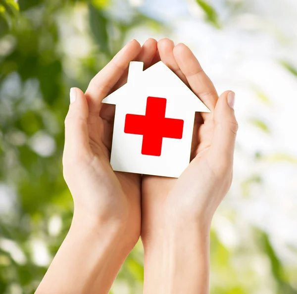 Руки, держа бумаги дом с Красного Креста — стоковое фото