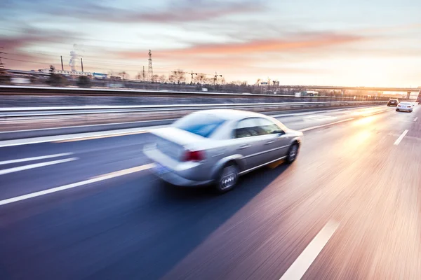 Автомобиль, едущий на автостраде на закате, размытом изображении — стоковое фото