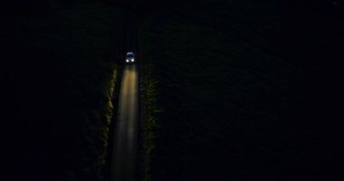 Автомобильные фары вождения ночью в темноте. Воздушный снимок сверху — стоковое видео
