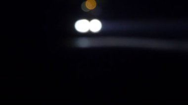 Движущегося автомобиля с огнями ночью. Автомобиль, идя на пустой ночной дороге. В полной темноте видно только яркий свет фар автомобиля — стоковое видео